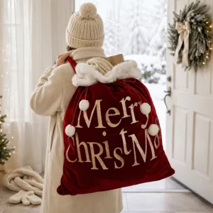 Sac cadeau de Noël en velours rouge avec texte pailleté or et bordure en peluche, détail de déco.