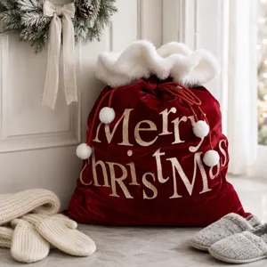Sac cadeau de Noël en velours rouge avec bordure en fausse fourrure blanche et lettrage doré.