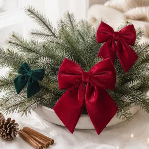Détail de nœuds de Noël en velours avec textures de fêtes rouges et vertes et branches.