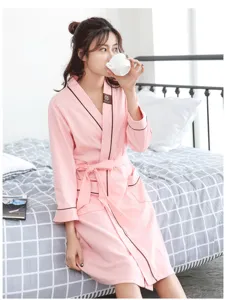 Women's pink long sleeve cotton bathrobe with contrast brown piping and belt for sleepwear.