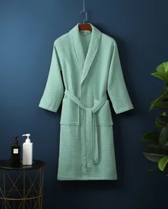 Detailed view of the soft waffle-weave bathrobe hanging on wall with clean bathroom staging.