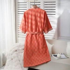 Detailed view of the orange cotton gauze bathrobe hanging on a rack with home decor setting.