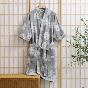 Detail view of cotton double-layer gauze bathrobe with floral print and belt hanging on shoji screen.