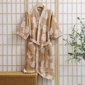 Detail shot of floral cotton bathrobe hanging on wooden hanger with natural background setup.