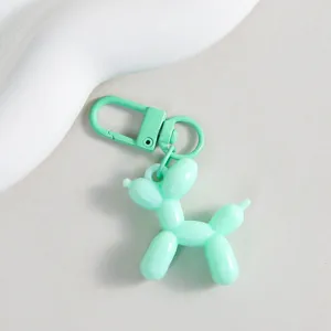 Close-up of a cute mint green balloon dog keychain charm, glossy finish, stylish bag accessory.