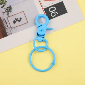 Gros plan détaillé d'un mousqueton pivotant en métal bleu vif et anneau de clés pour accessoires.