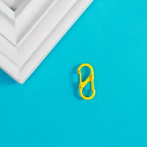 Mousqueton à ressort en S jaune vue de détail, porte-clés en métal et accessoire de sac DIY.