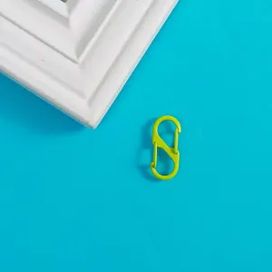 Détail de mousqueton à ressort en S vert, fermoir en métal pour bijoux DIY et porte-clés.