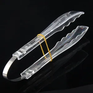 Transparent plastic food tongs detail, clear kitchen buffet baking tool close up view