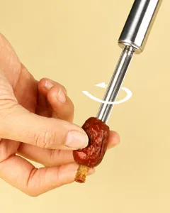 Detail view of a stainless steel date pitter tool in action, demonstrating core removal for red dates.
