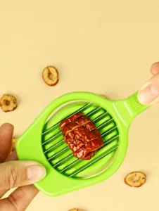 Green plastic red date slicer detail view, multi-blade fruit cutting kitchen tool