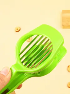 Green plastic red date pitter and slicer with stainless steel blades, detail shot.