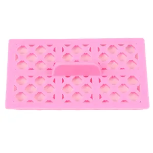 Détail du moule à fondant rose en plastique, gaufrage losange avec poignée centrale.