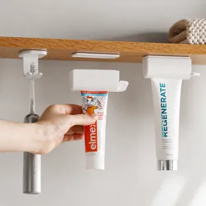 Magnetische tandpastadispenser en hangende tandenborstelhouder voor wandmontage in de badkamer.