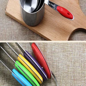 Stainless steel measuring cup and spoon detail view featuring colorful silicone handles for kitchen.