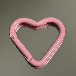 Close-up detail of a pink heart-shaped metal carabiner keychain accessory showing smooth paint.