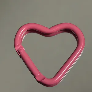 Close-up of pink heart-shaped aluminum carabiner hook, smooth painted surface, key ring accessory.