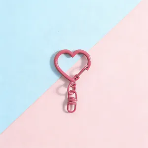 Close-up detail of a pink heart-shaped metal keychain charm and lobster clasp accessory.