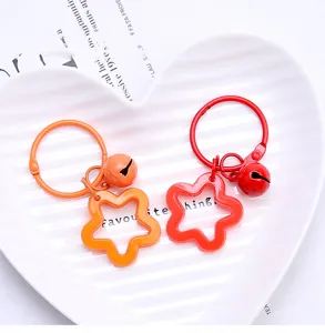 Close-up detail of cute metal pentagram star keychain with mini bell, vibrant bag charm.