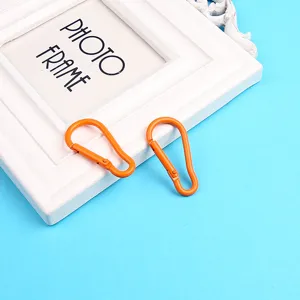 Primo piano dettagliato di moschettoni a molla in alluminio arancione su cornice bianca.