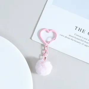 Gros plan du porte-clés en cœur rose avec un pompon duveteux. Élégant accessoire de sac.