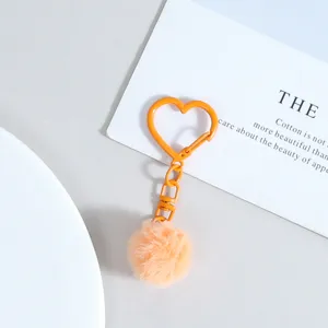 Détail de porte-clés cœur orange avec un joli pom-pom duveteux et fermoir pour sacs.
