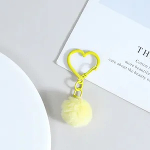 Porte-clés mousqueton en métal en forme de cœur jaune avec pompon en peluche douce pour sac.