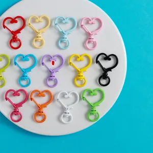 Gros plan mousquetons colorés en forme de cœur, anneaux ressort en alliage pour bijoux DIY.