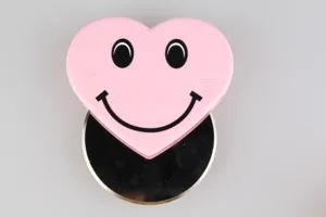 Cute pink heart smiley face pizza cutter with stainless steel rolling blade for baking tool use.