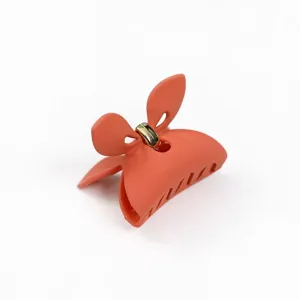 Primo piano di un clip per capelli opaca arancione con grazioso fiocco e cerniera.