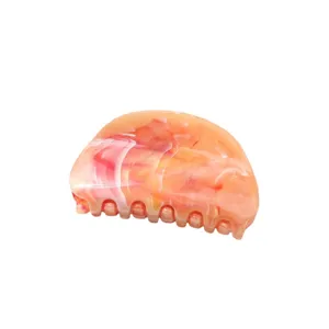 Close-up detail of a colorful peach marbled hair claw clip, showing its smooth texture and teeth.