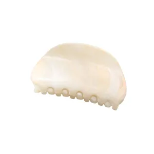 Closeup of minimalist arch hair claw clip in cream marble pattern for daily chic hairstyling.