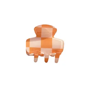 Dettaglio molletta per capelli in acrilico a quadretti arancione bianco, accessorio.