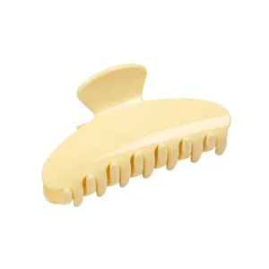 Detail view of a solid butter yellow acrylic hair claw clip showing smooth curves and teeth.