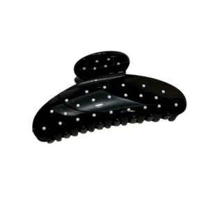Detailed view of a black hair claw clip with white polka dots, stylish hair accessory for women.