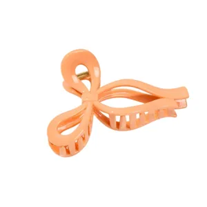 Close-up detail of the peach orange bow hair claw clip, showing hollow texture and finish.