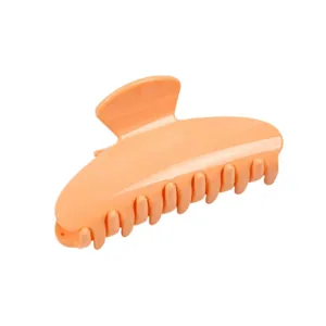 Close-up detail of a bright orange hair claw clip featuring a classic bow shape and strong teeth.