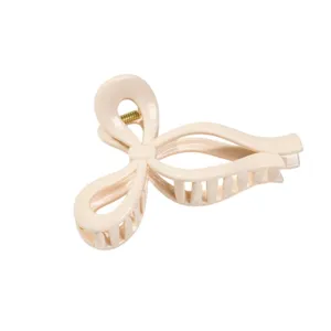 Detail shot of a chic beige bow hair claw clip, featuring smooth resin finish and spring.