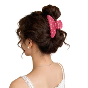 Detailed view of a sweet pink polka dot hair claw clip worn on a elegant curly bun hairstyle.