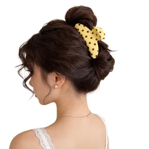 Charming polka dot hair claw clip detail view, stylish yellow hair accessory for elegant use.