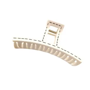 Detailed close-up of a large curved hair claw clip with cream white and black stitch pattern.