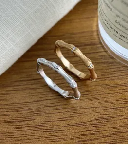 Vue détaillée de bagues style bambou bicolores avec pierres étincelantes sur bois.