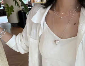 Detailopname van gelaagde zilveren hart- en kruiscollars, elegante 925 zilverstijl.
