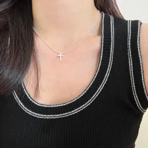 Detailopname van een delicate zilveren bolletjesketting met een minimalistische kruishanger.