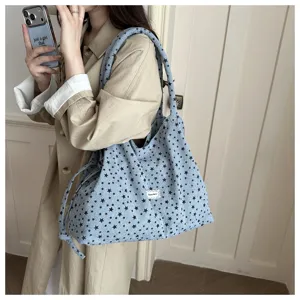 Vista detallada de bolso tote azul informal con estrellas negras llevado en interior.
