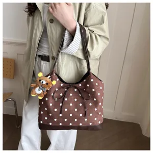 Vista dettagliata della borsa a spalla in camoscio a pois, con fiocco e ciondolo orsetto di peluche.