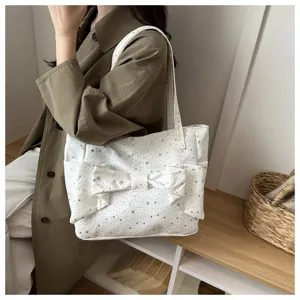 Vista dettagliata della borsa a spalla in tela bianca con fiocco carino e stampa di stelle.