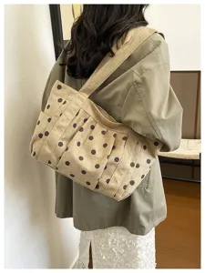 Vista dettagliata della borsa tote in tela beige a pois con molteplici tasche esterne.