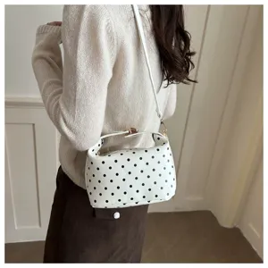 Detail view of white polka dot shoulder handbag, featuring compact size, classic pattern, and dual straps.