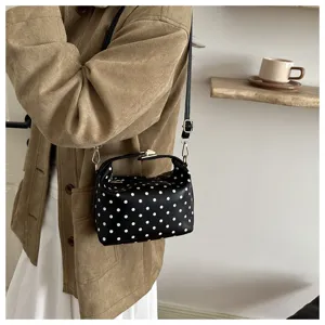 Detailed view of a stylish black cosmetic bag featuring classic white polka dots and chic gold hardware.